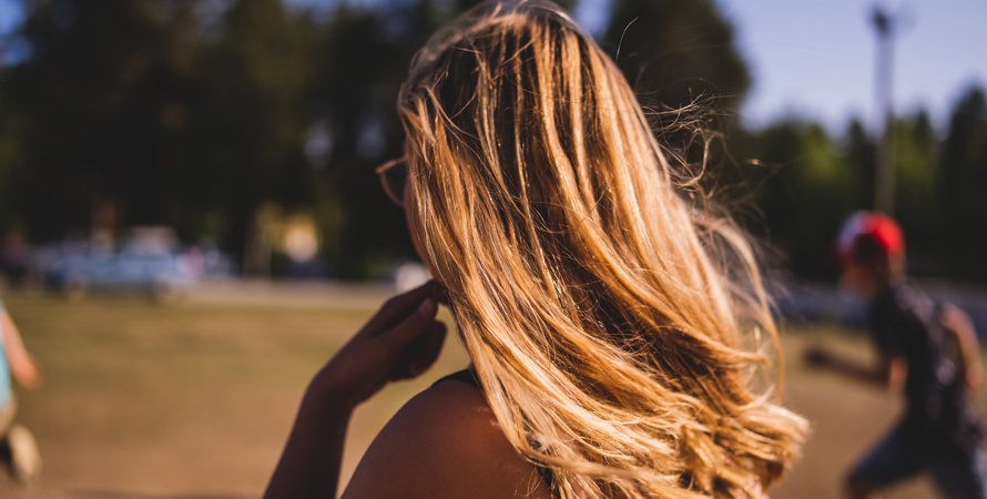 En ung person med långt ljust hår som tittar bort från kameran.