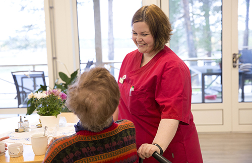 Äldre kvinna i särskilt boende tillsammans med undersköterska. De ler mot varandra.