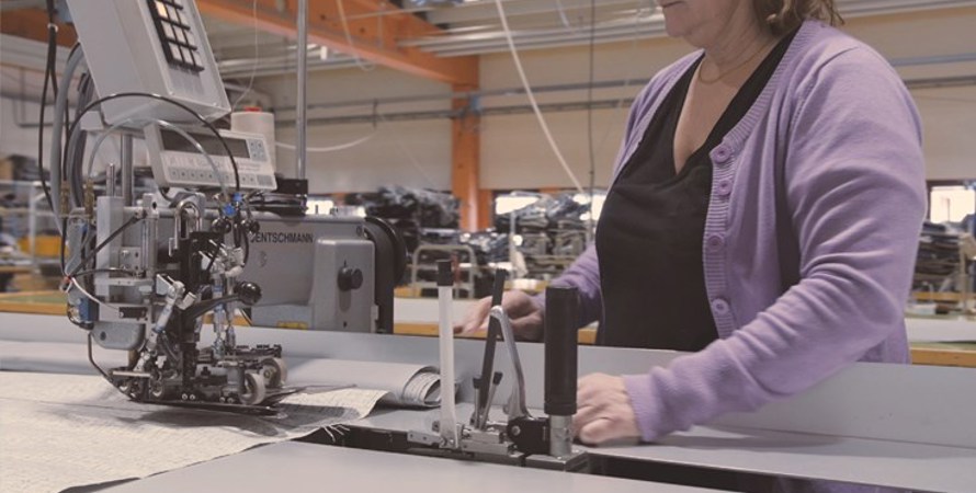 En kvinna står vid en industriell symaskin
