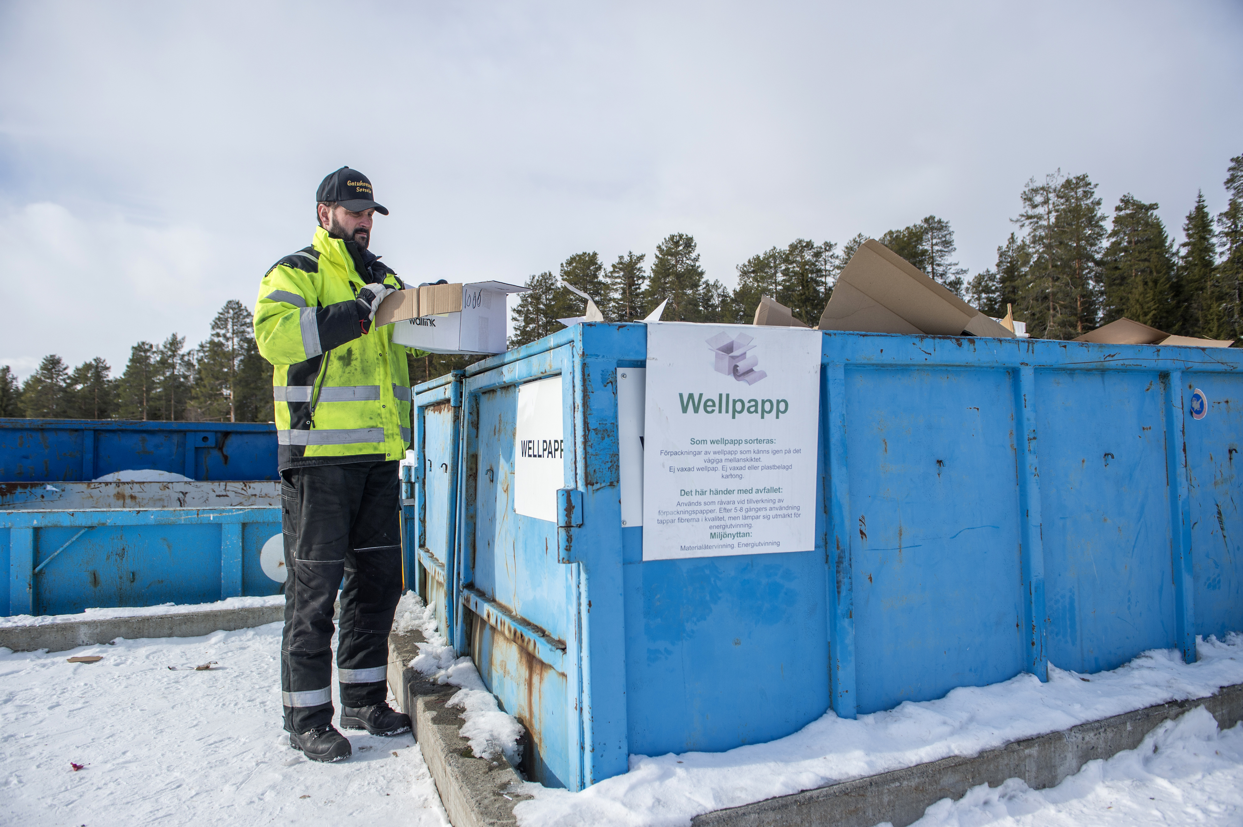 En man står invid en blå container 